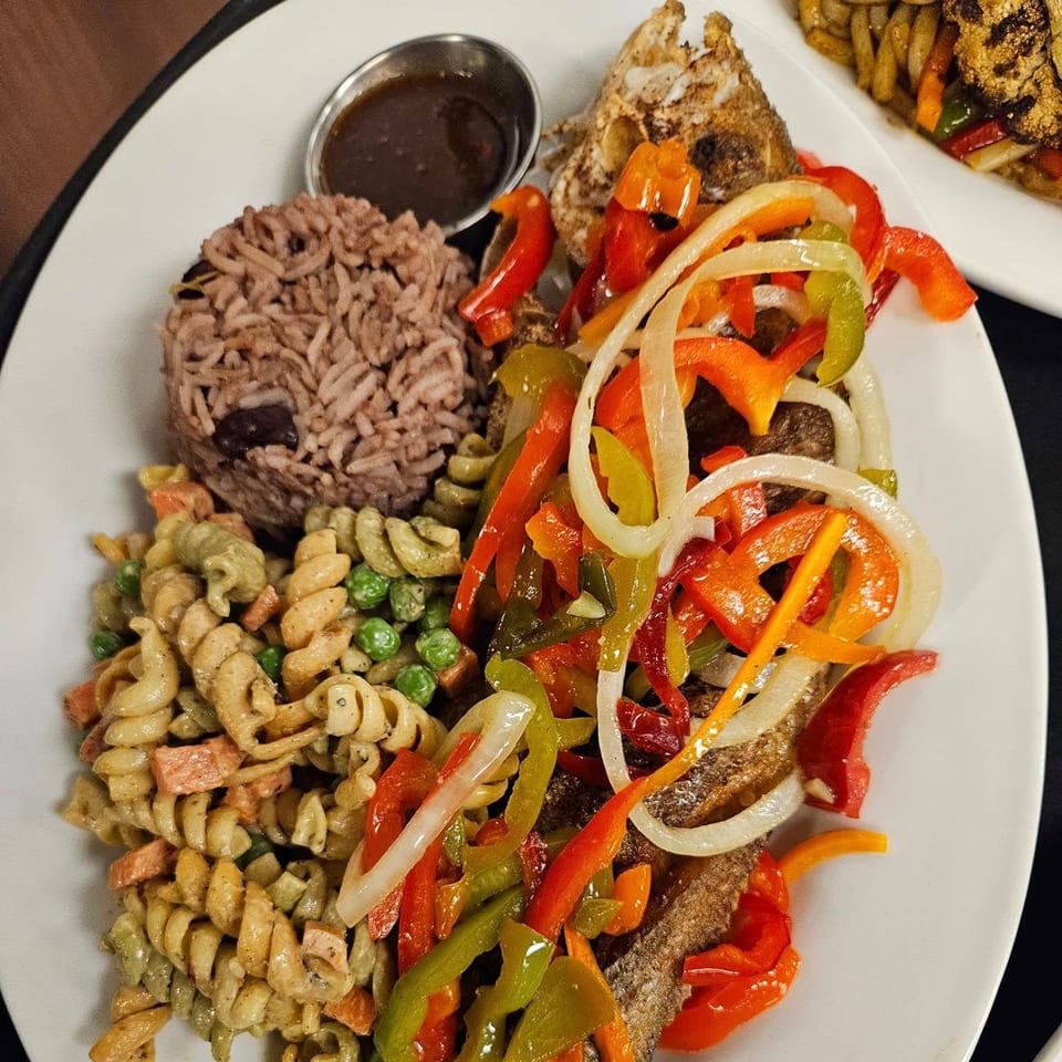 Jamaican escovitch fish with rice and peas, pasta salad, and a side of sauce.