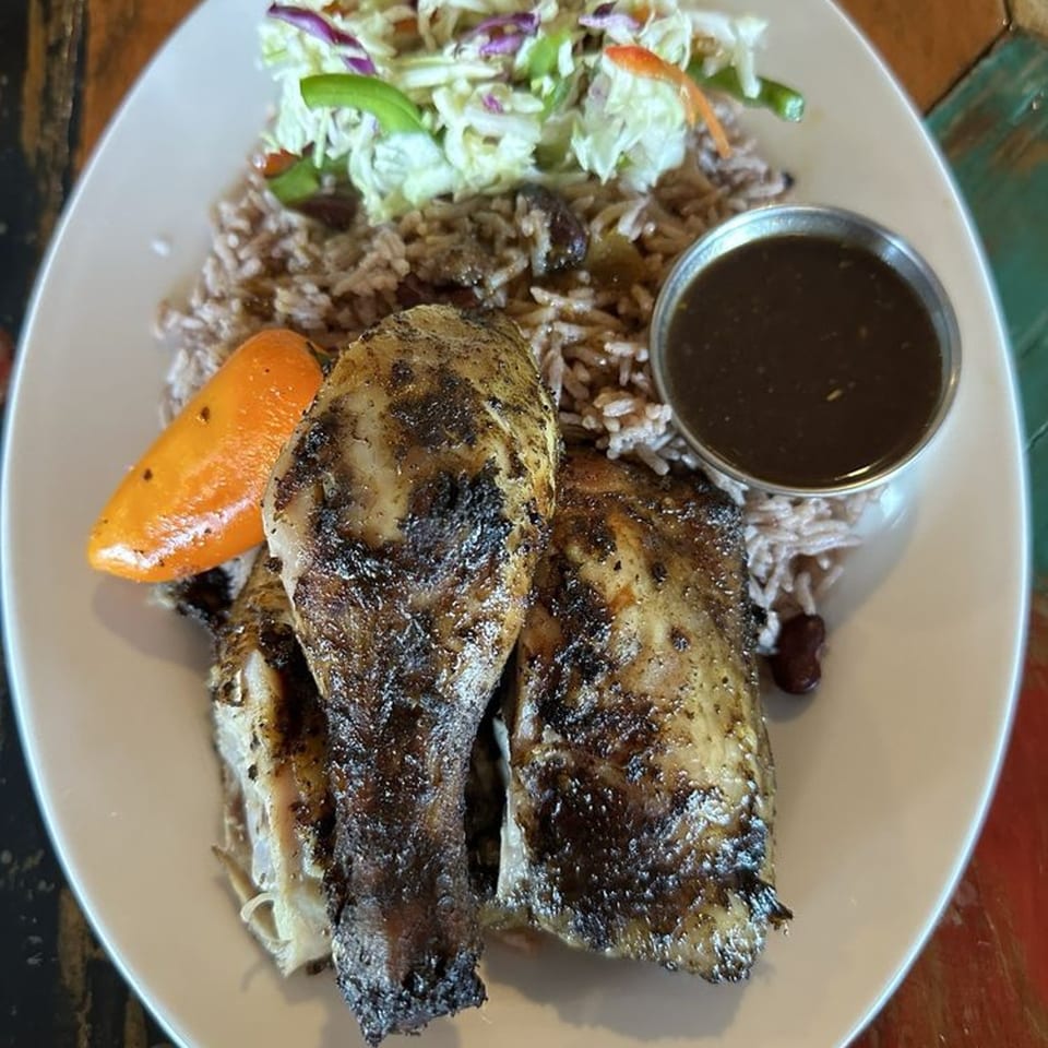 Topnotch Island Flavor Kitchen's jerk chicken with rice, peas, coleslaw, and a side of sauce.