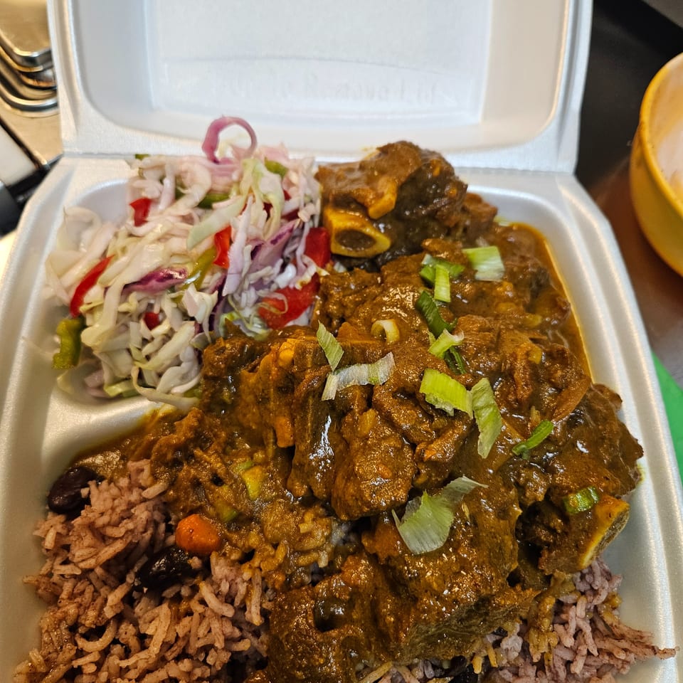 Topnotch Island Flavor Kitchen's Jamaican oxtail stew with rice and peas, and coleslaw in a takeout container.