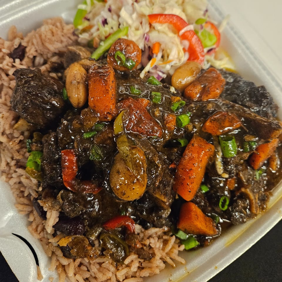 Topnotch Island Flavor Kitchen's Jamaican oxtail stew with rice and peas, carrots, and a side of coleslaw.